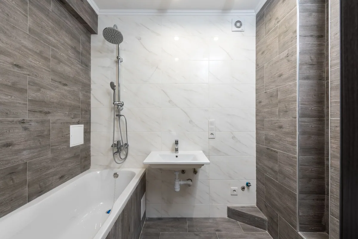 Baño con bañera, ducha y lavabo con el sifón del desagüe a la vista