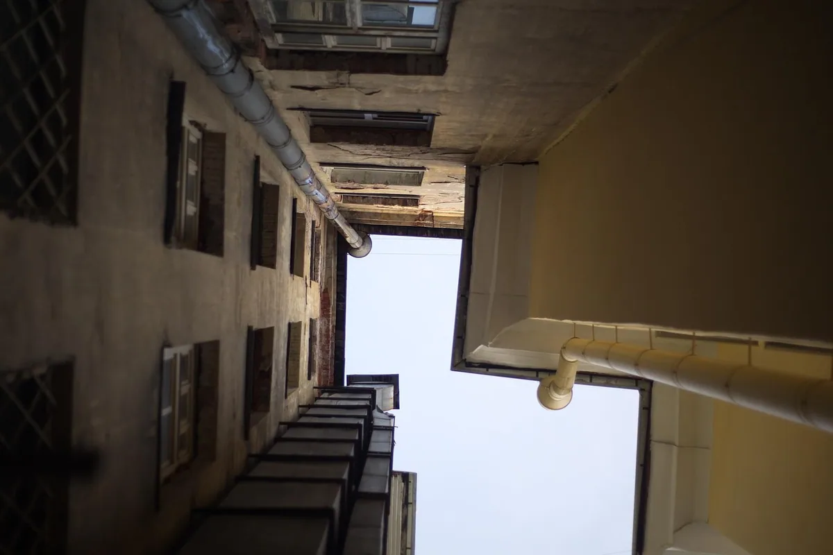 Patio de luces de una comunidad de vecinos visto desde abajo, con las bajantes en las paredes