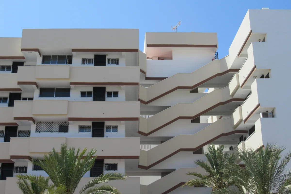 Bloques de apartamentos de Playa del Inglés, en San Bartolomé de Tirajana, con balcones corridos, escaleras exteriores y palmeras delante