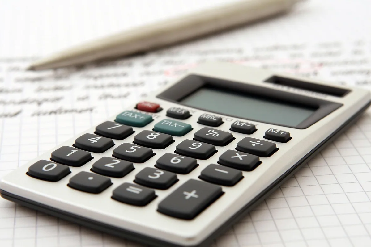 Calculadora y bolígrafo sobre una hoja con anotaciones para calcular el precio de un desatasco