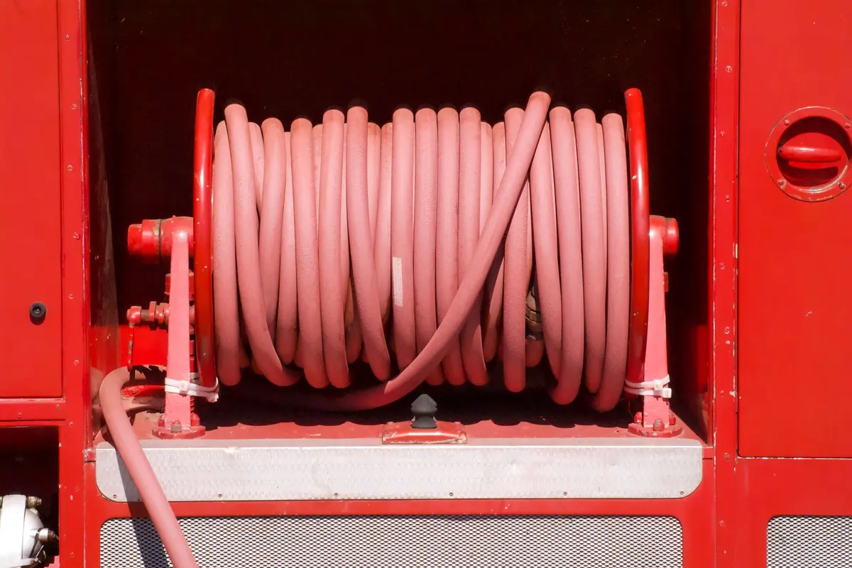 Carrete con una manguera roja enrollada en el compartimento de un camión